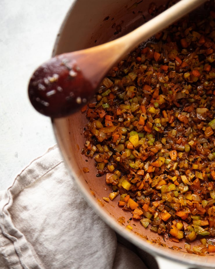 Image shows some cooked down vegetables and herbs in a pot.