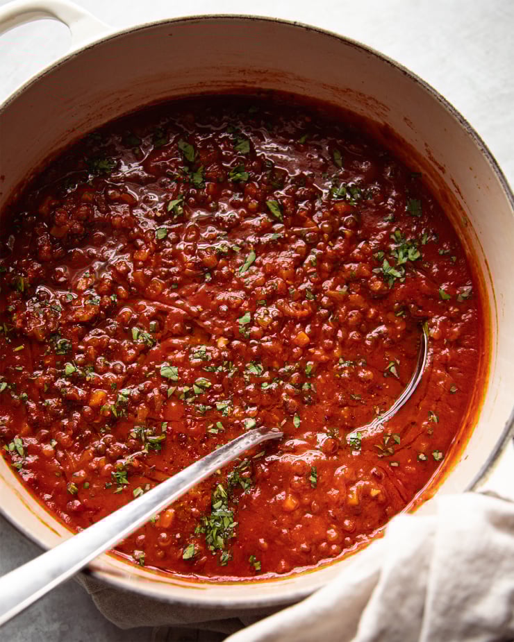 Image shows an overhead glance at a big Dutch oven filled with a deep red soup that’s flecked with bits of chopped parsley.