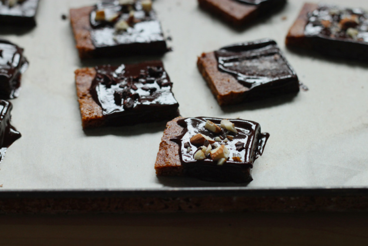 a 3/4 angle image shows some chocolate hazelnut grahams on a baking sheet, sprinkled with chopped hazelnuts.