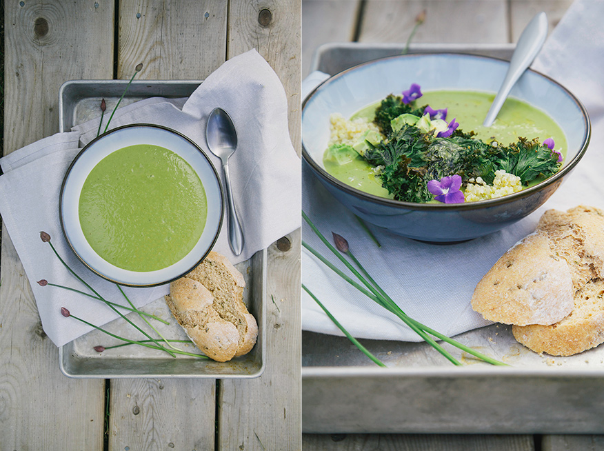 Two images show a bowl of mellow and creamy green asparagus soup. The osup is garnished with kale chips and violet flowers. There are slices of bread to the side.