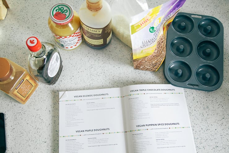An overhead shot shows an open cookbook and baking ingredients on a kitchen counter