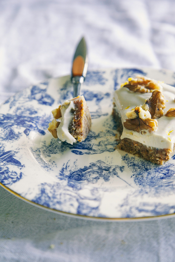 A 3/4 angle shot shows a raw and vegan carrot cake slice on an ornate blue-patterned plate.