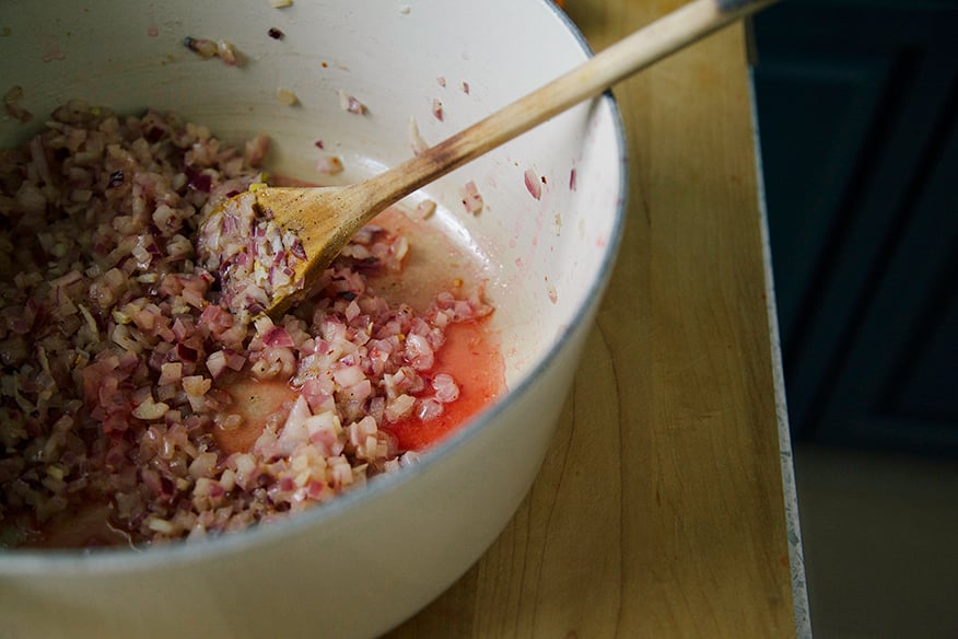 Image shows onions sauteeing in a pot.