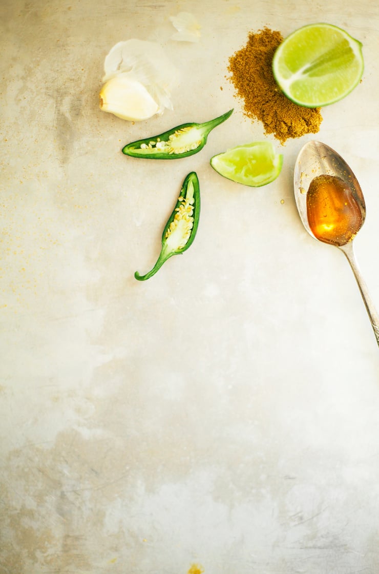An overhead shot of ingredients for a cumin garlic sauce on a metal background.