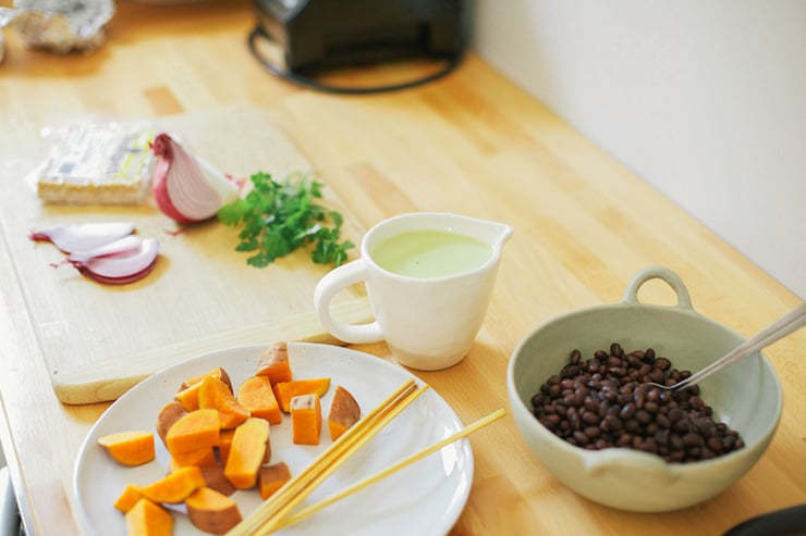 Image shows ingredients for a sweet potato burrito bowl on a kitchen counter.