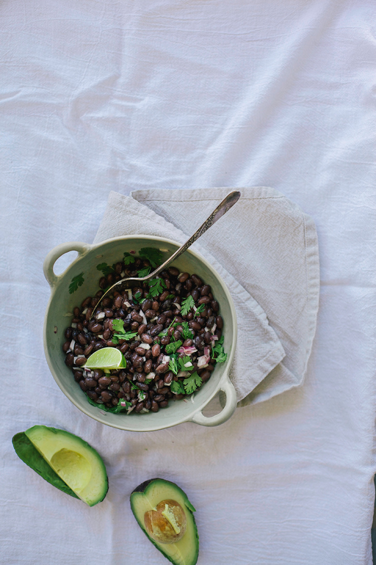 An overhead shot of a bowl of black beans tossed with cilantro and red onion.