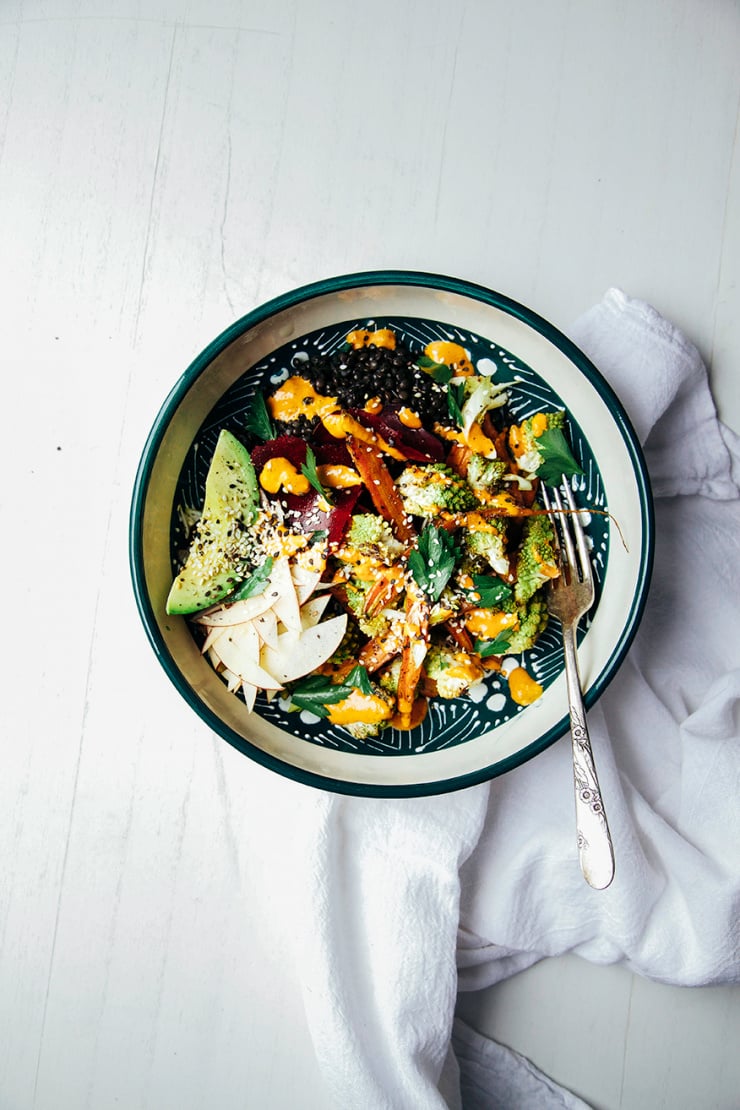An overhead shot of a fall veg + lentil bowl with goji ginger tahini cream
