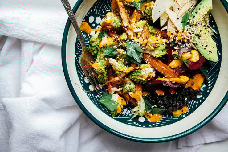 An overhead shot of a fall veg + lentil bowl with goji ginger tahini cream