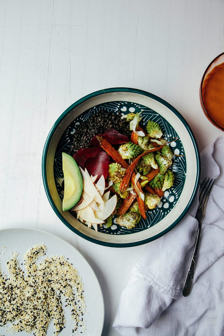 An overhead shot of a fall veg + lentil bowl with goji ginger tahini cream