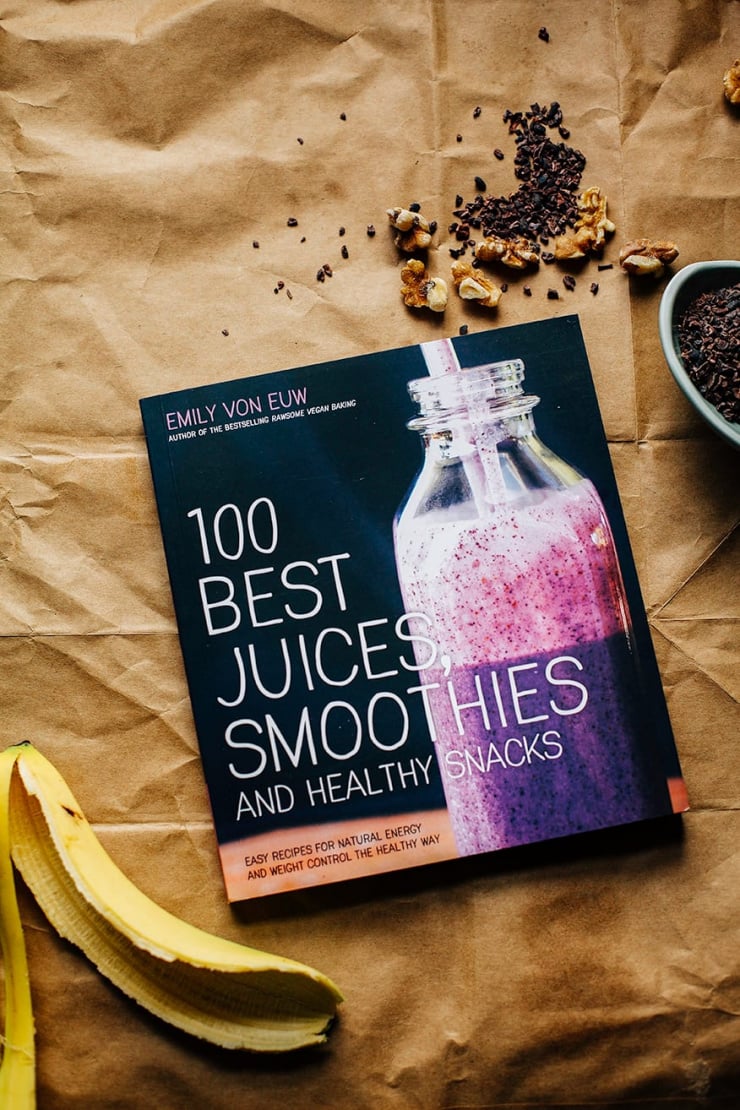 Emily Von Euw's "100 Best Juices, Smoothies & Healthy Snacks" An overhead shot of Emily Von Euw's "100 Best Juices, Smoothies & Healthy Snacks" cookbook on a brown paper background.