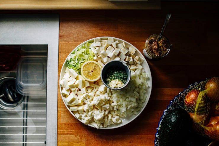 for a dreamy winter vegetable chowder // @thefirstmess An overhead shot of chopped winter vegetables, all arranged on a white plate on top of a butcher block countertop.
