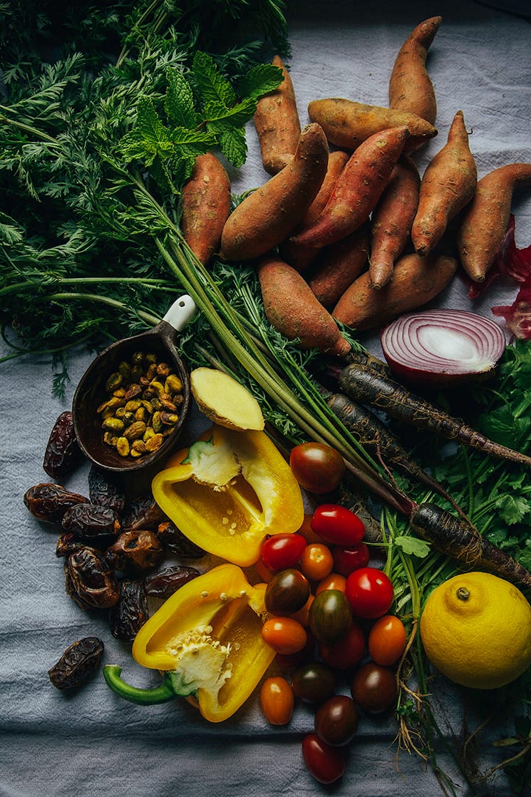 An overhead shot of ingredients for a sweet potato salad with vegetables, dates, pistachios and mint.