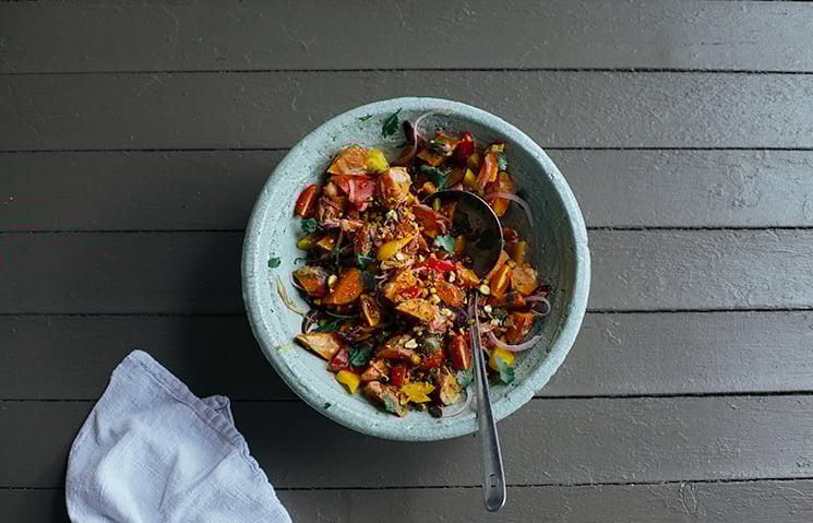 An overhead shot of a sweet potato and vegetable salad in a light green bowl.