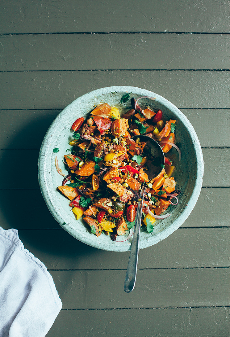 An overhead shot of a sweet potato and vegetable salad in a light green bowl.