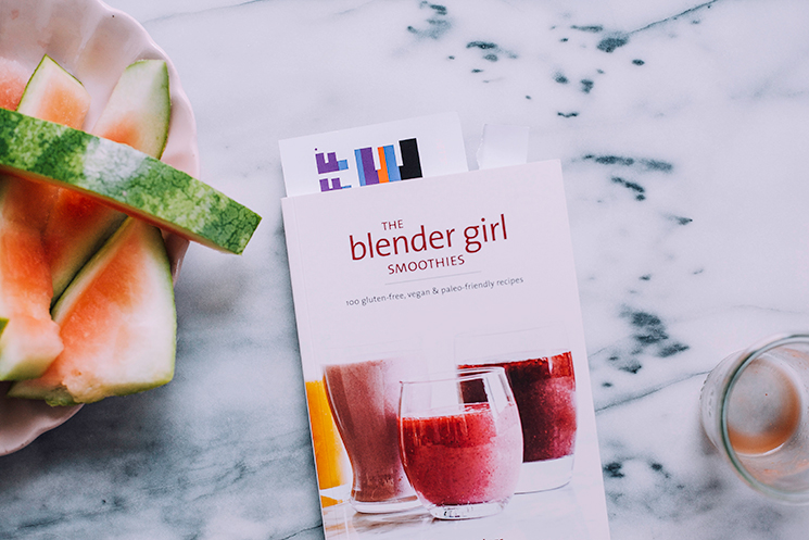 Overhead shot of “The Blender Girl: Smoothies” cookbook on a white marble background.