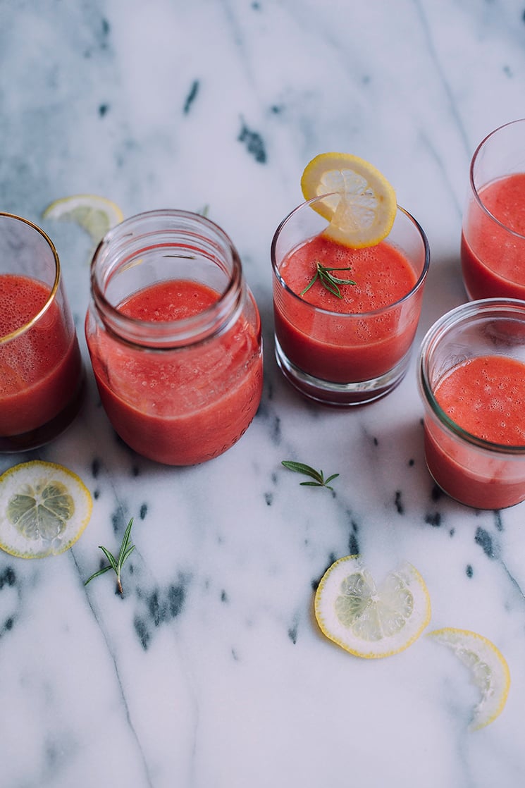 An overhead shot of bright pink frozen watermelon-ade in 5 different, clear glasses. Glasses are filled at the halfway mark and are on top of a marble background.