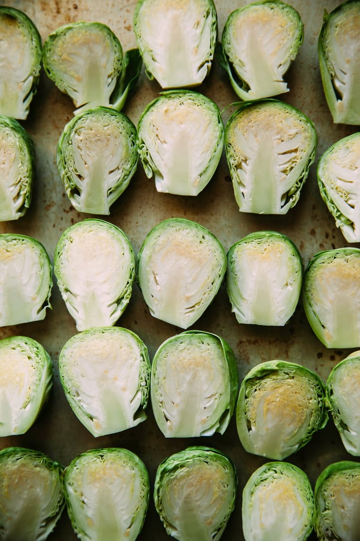 An up close, overhead shot of halved Brussels sprouts facing up on a baking sheet.