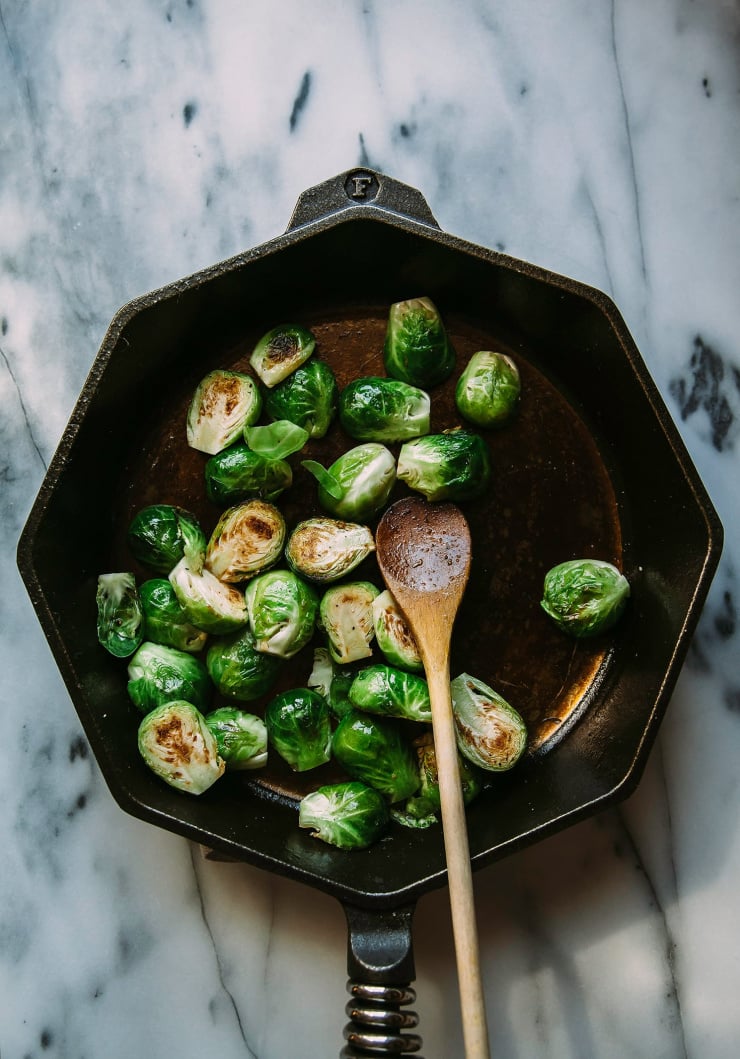 An overhead shot of Brussels sprouts searing in a hexagonal cast iron pan.