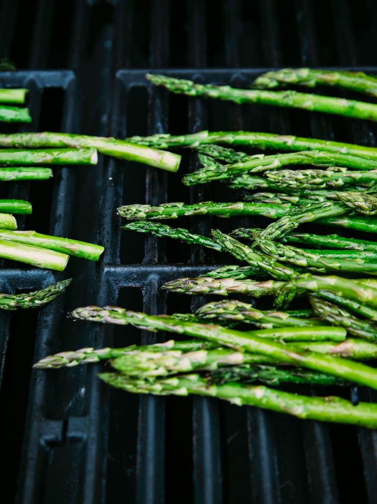 An up close shot of asparagus cooking on an outdoor grill.