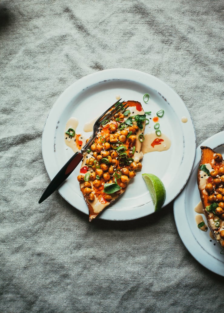 An overhead shot of a vegan stuffed sweet potato with chickpeas on a white plate.