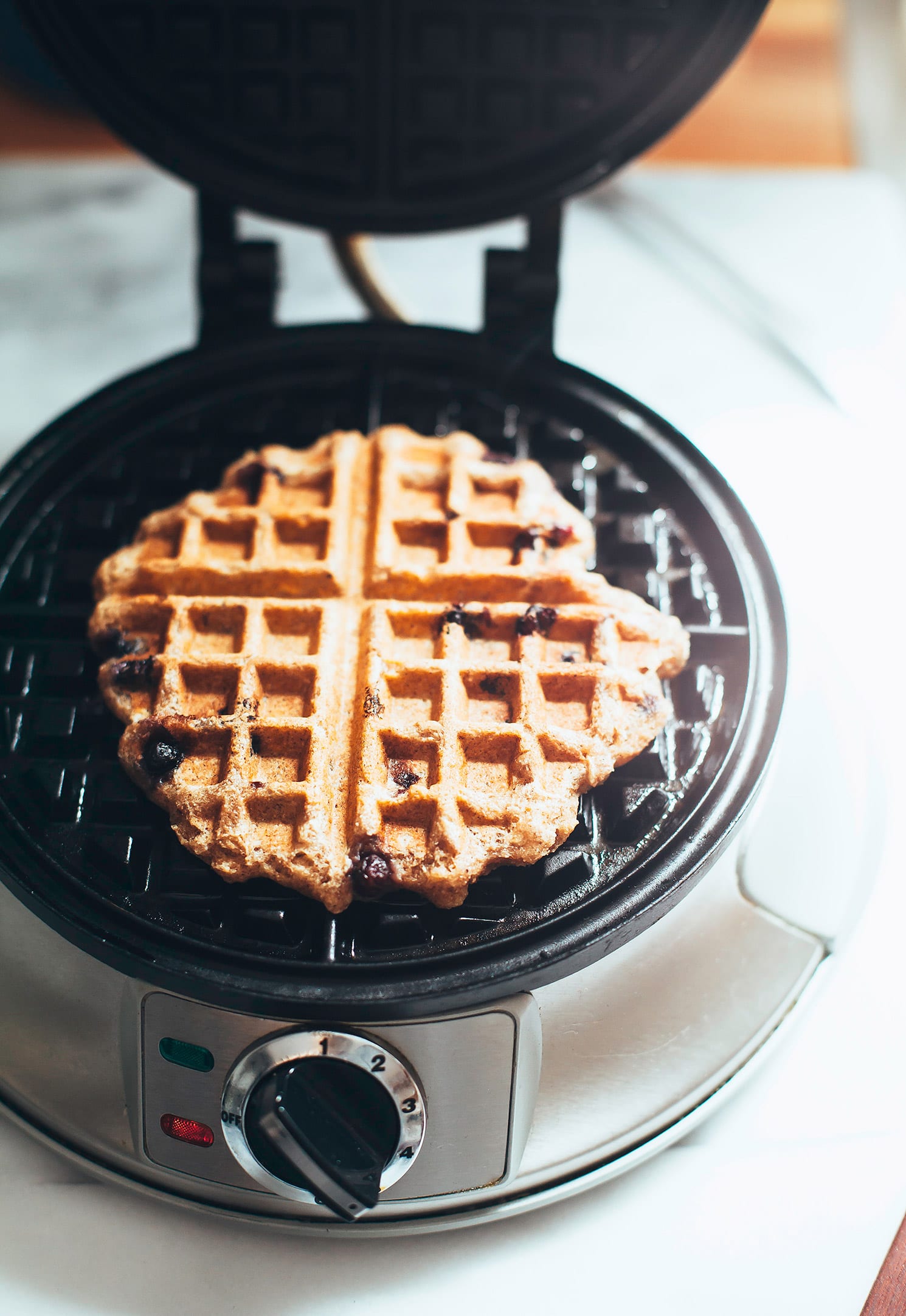 A 3/4 angle image shows a cooked waffle in an open waffle iron.