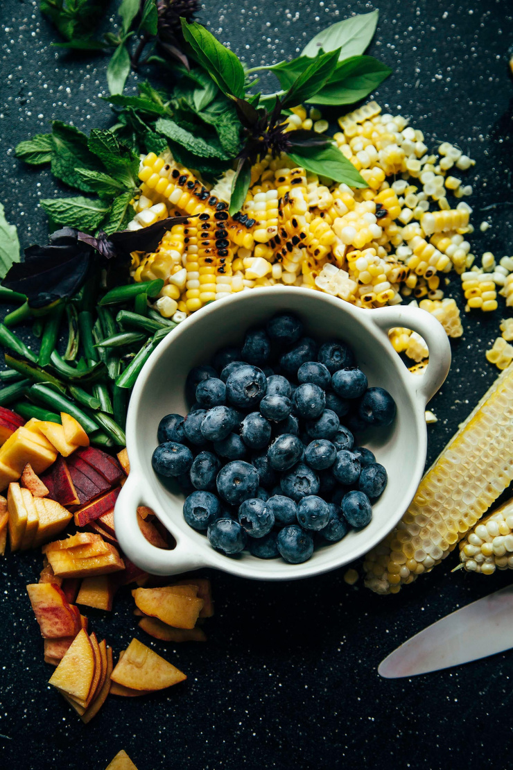 An overhead shot of ingredients for a summery grain salad on a cutting board.