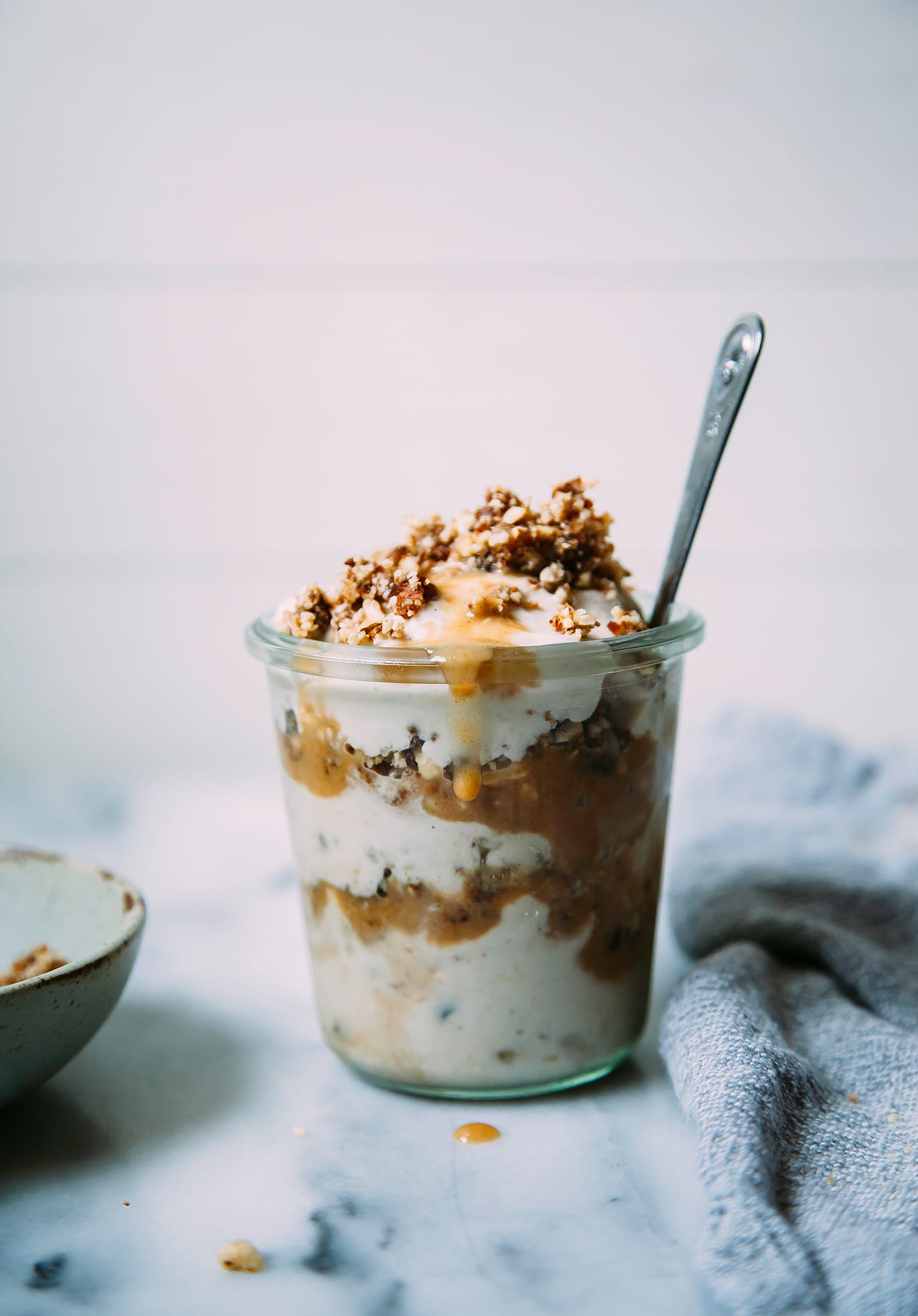 A head on shot of a vegan peanut caramel sundae layered in a glass jar.