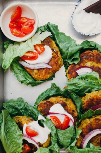 An overhead shot of a metal tray filled with lettuce-wrapped golden split pea patties.
