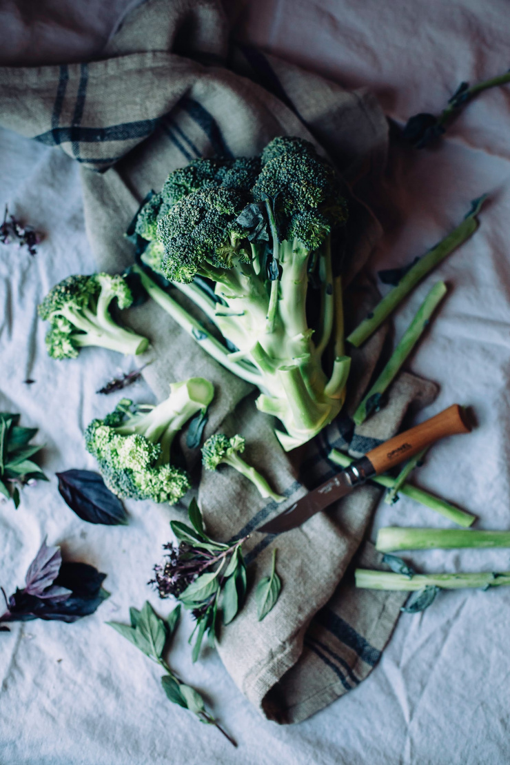 An overhead shot of a head of broccoli being trimmed.