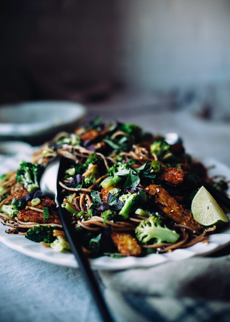 A head on shot of a platter of noodles and broccoli garnished with herbs
