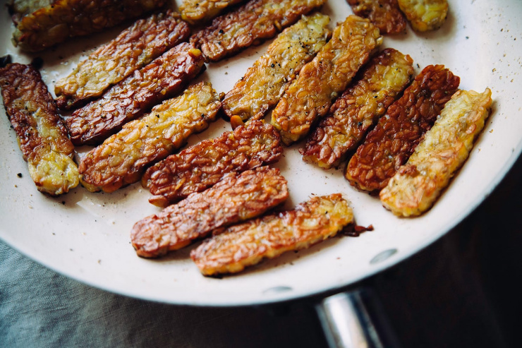 An overhead shot of pieces of tempeh being browned in a skillet.