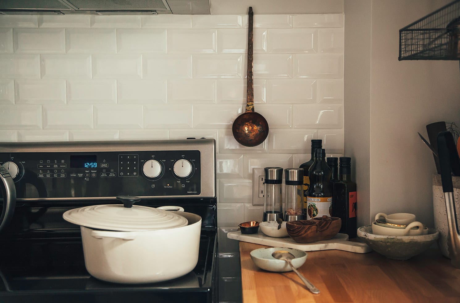 Image shows a white pot on an electric stove with botlles of oil and little bowls of spices nearb y on the counter.