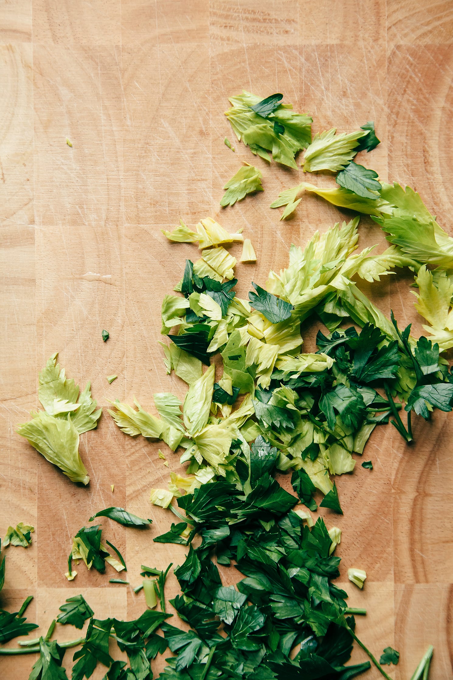 Image shows parsley and celery heart leaves on a cutting board.