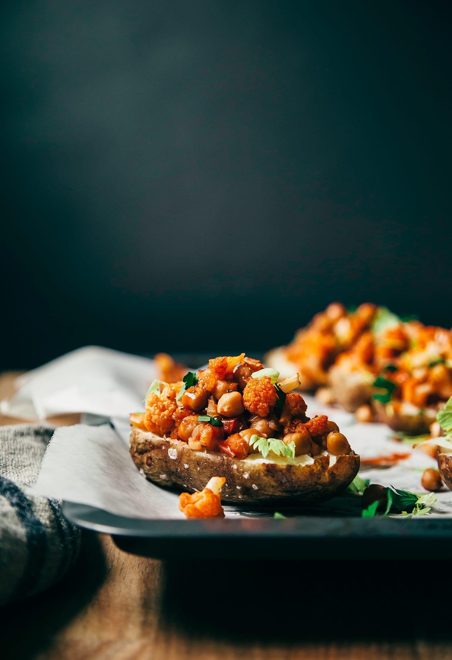 A head-on shot of a baked potato half filled with cauliflower, chickpeas, and Buffalo-style hot sauce.