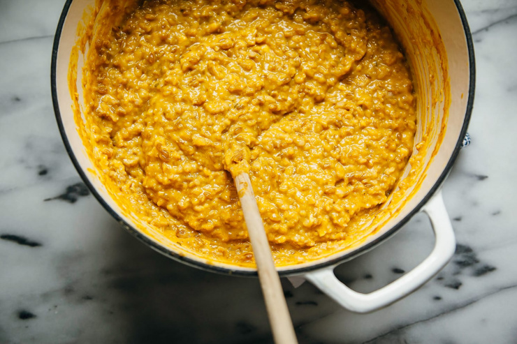 Image shows an orange-hued farrotto in a Dutch oven style pot.