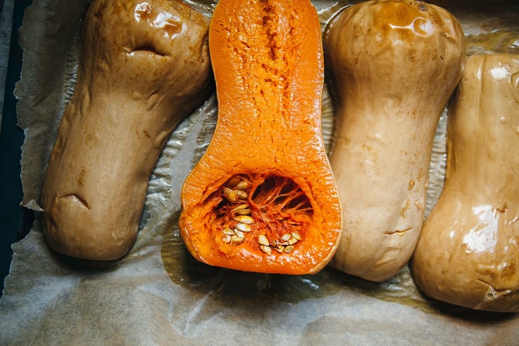 Image shows roasted butternut squash halves on a baking sheet.