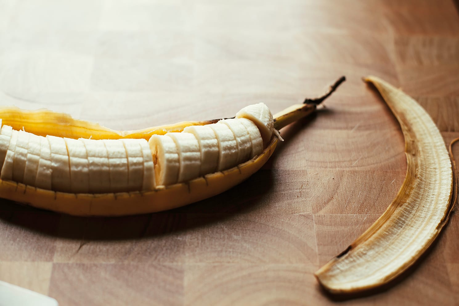 Image shows a sliced banana on a cutting board.