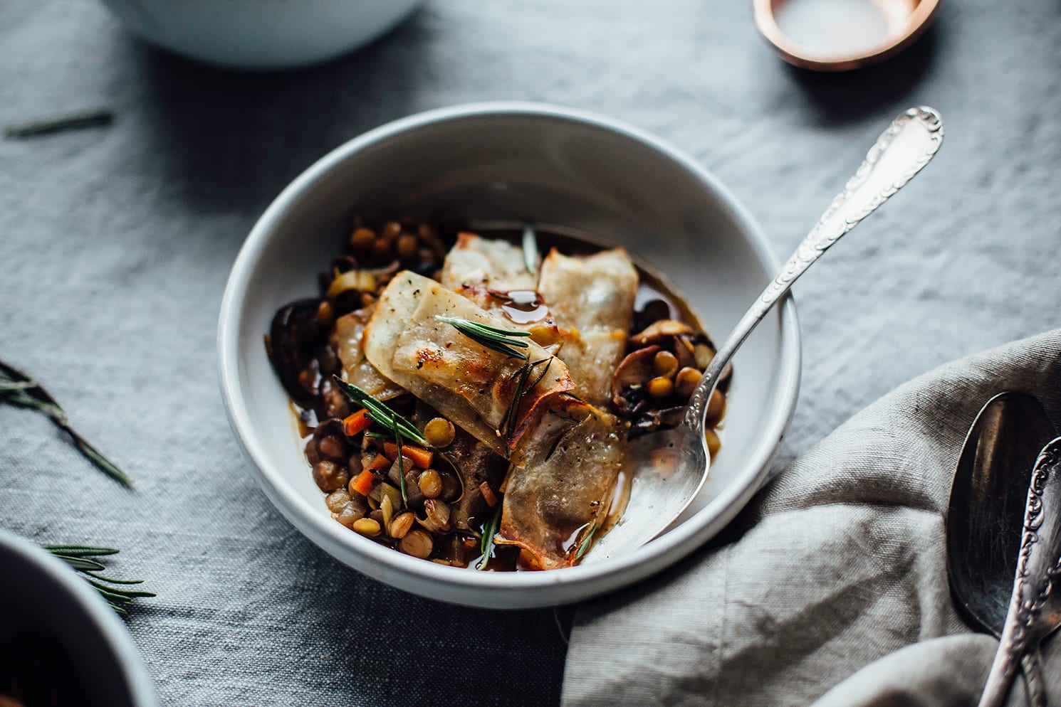 An overhead shot of baked balsamic lentil stew in individual serving bowls, topped with crispy potatoes.