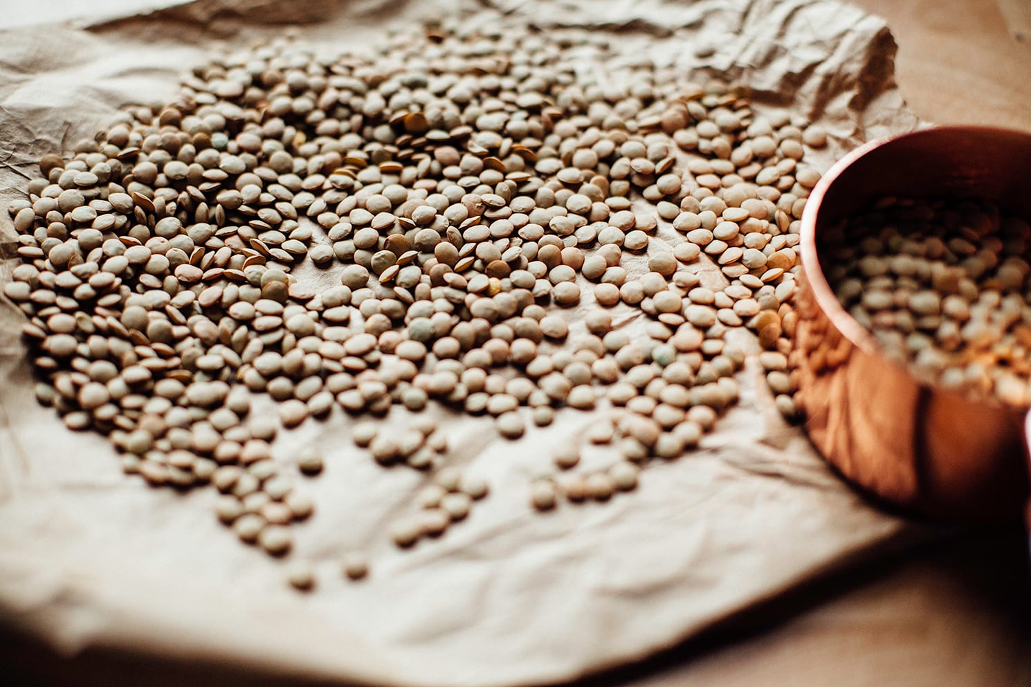 Image shows lentils scattered out on a piece of brown paper.