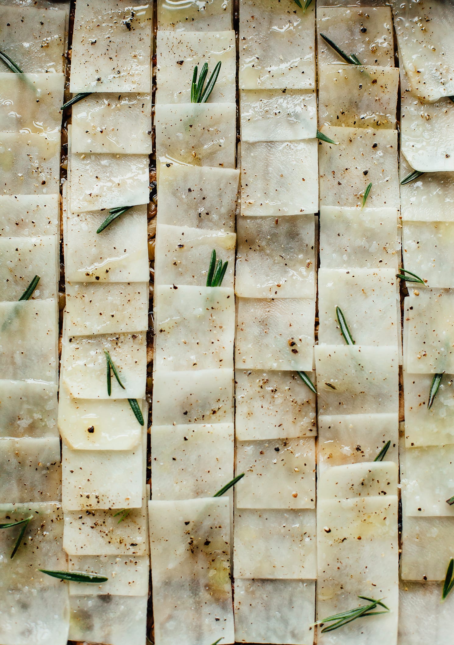 Image shows a baked balsamic lentil stew topped with thinly sliced potatoes, before baking.