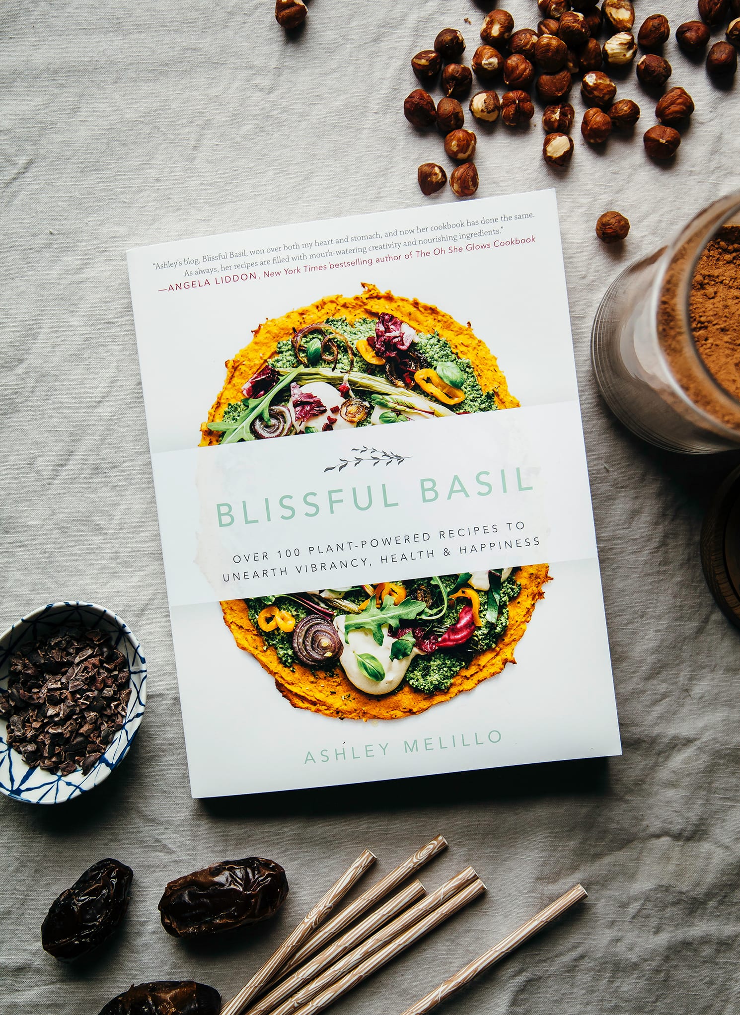 An overhead shot of the “Blissful Basil” cookbook on a beige linen background.