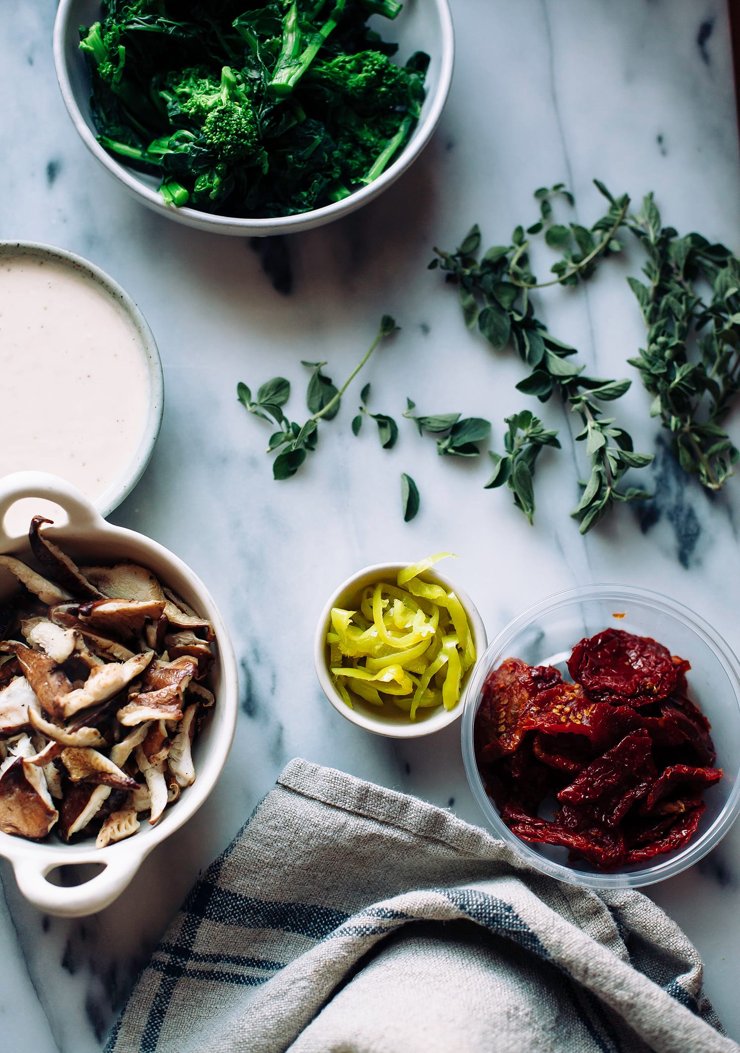 An overhead shot of prepped toppings for a pizza on a marble background.