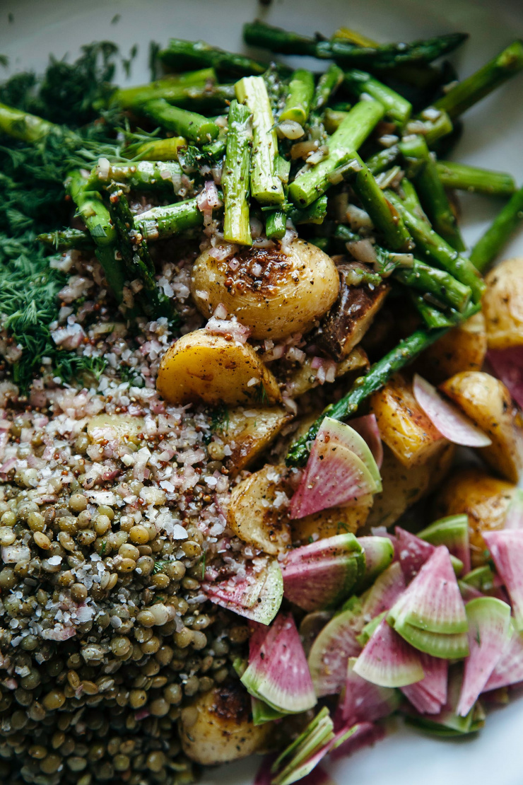 An overhead shot of roasted potato salad components in a wide bowl, before being mixed up.
