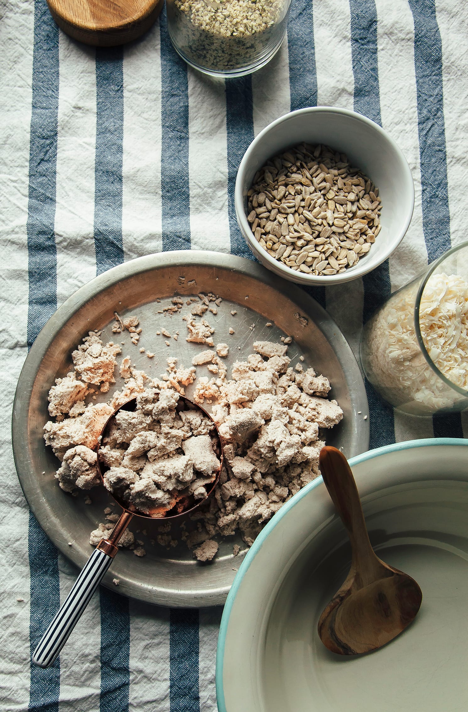 An overhead shot of ingredients used for nut pulp granola: nut milk pulp, sunflower seeds, hemp seeds, and shredded coconut.
