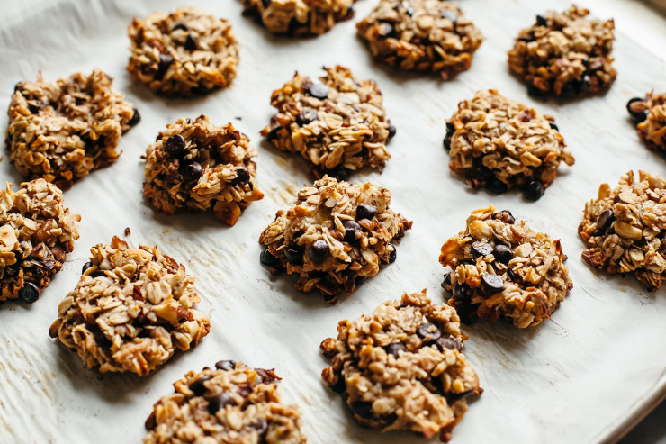 A 3/4 angle shot of banana chocolate chip breakfast cookies with oats on a baking sheet.