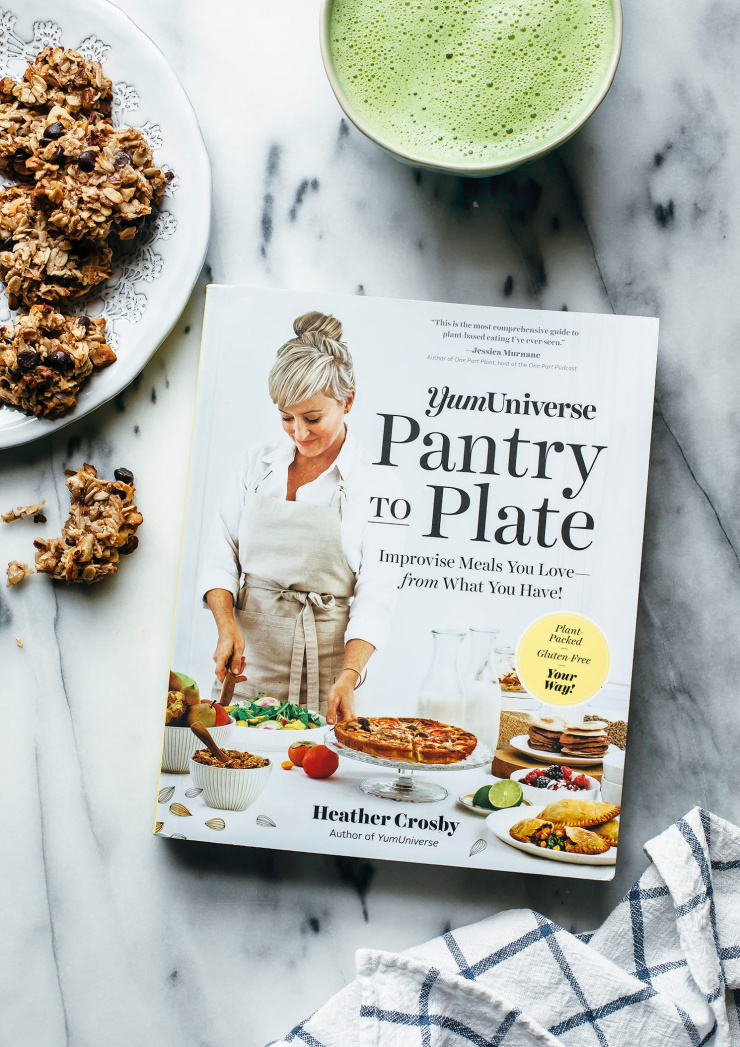 An overhead shot of the "YumUniverse Pantry to Plate" cookbook on a marble background.