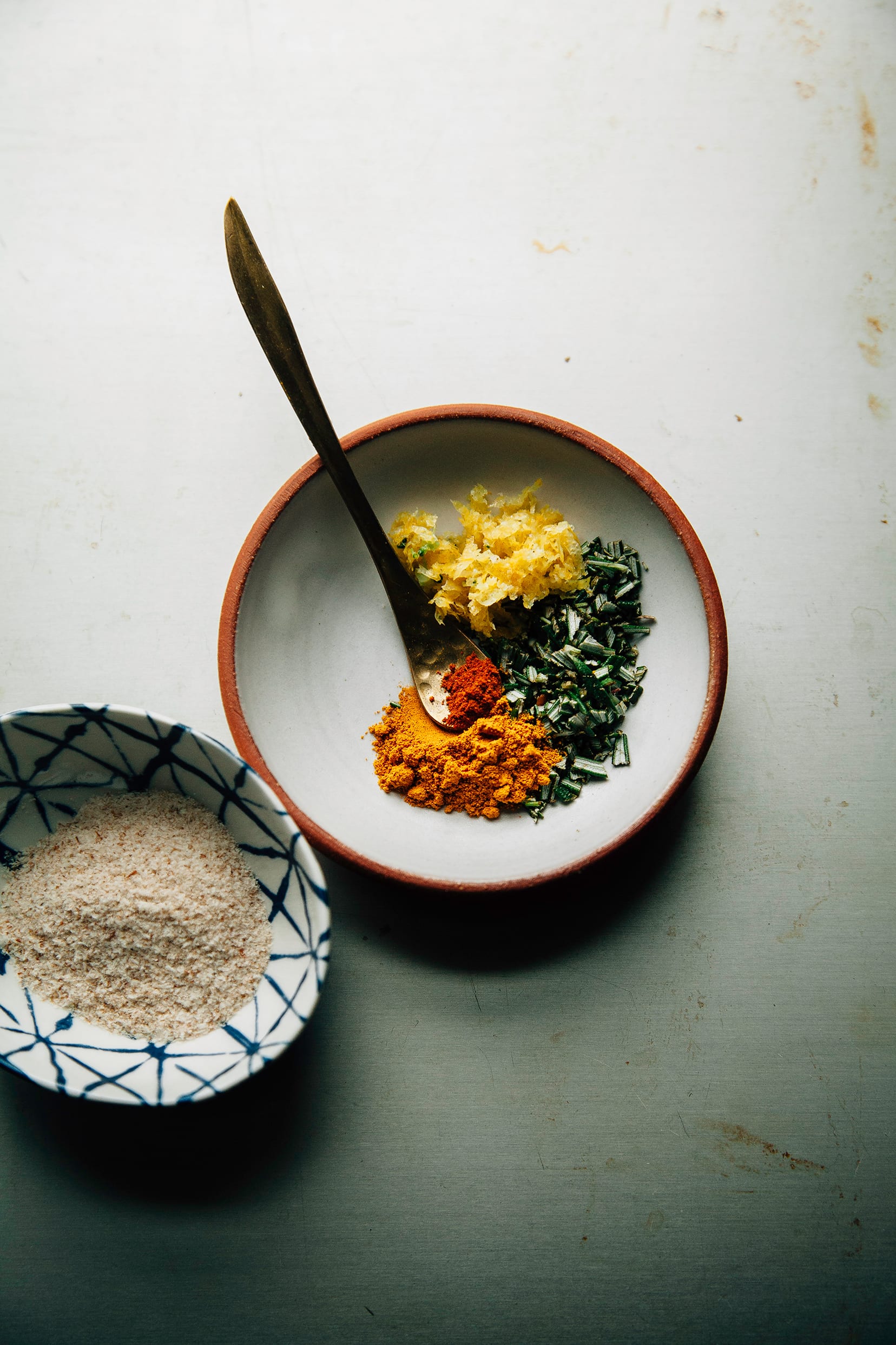 An overhead shot of a small bowl with chopped herbs and spices.