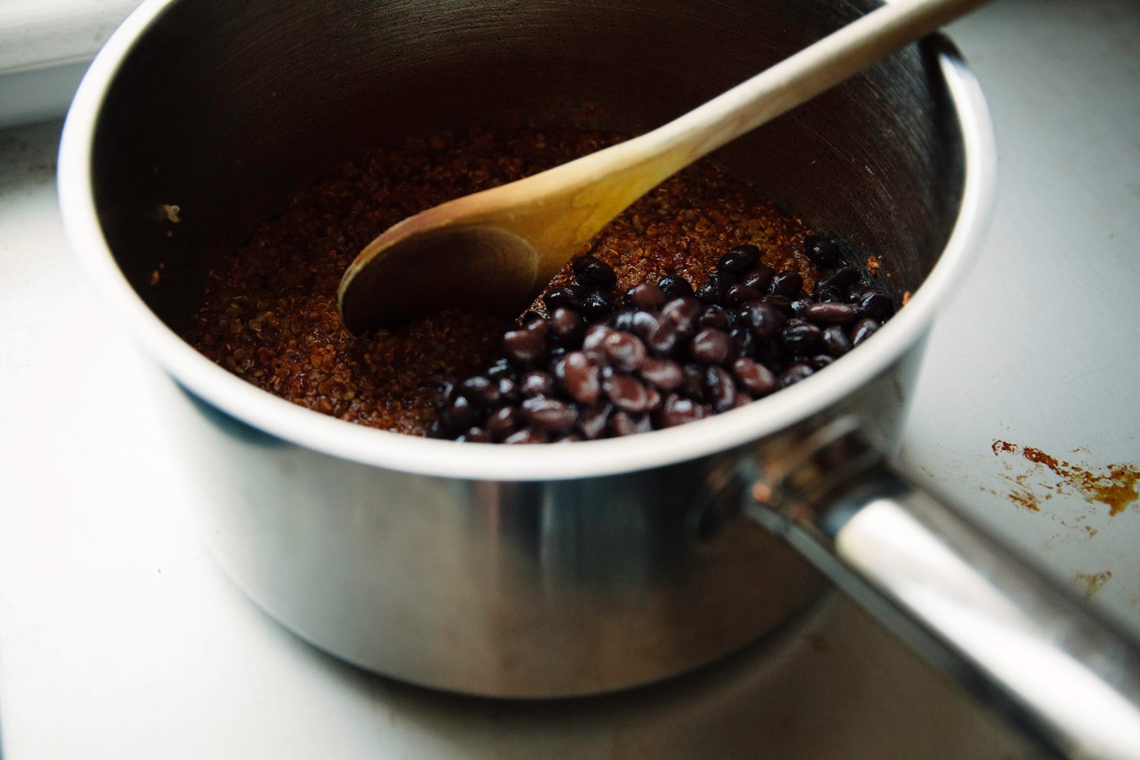 A 3/4 angle shot of spiced quinoa and black beans in a saucepan.