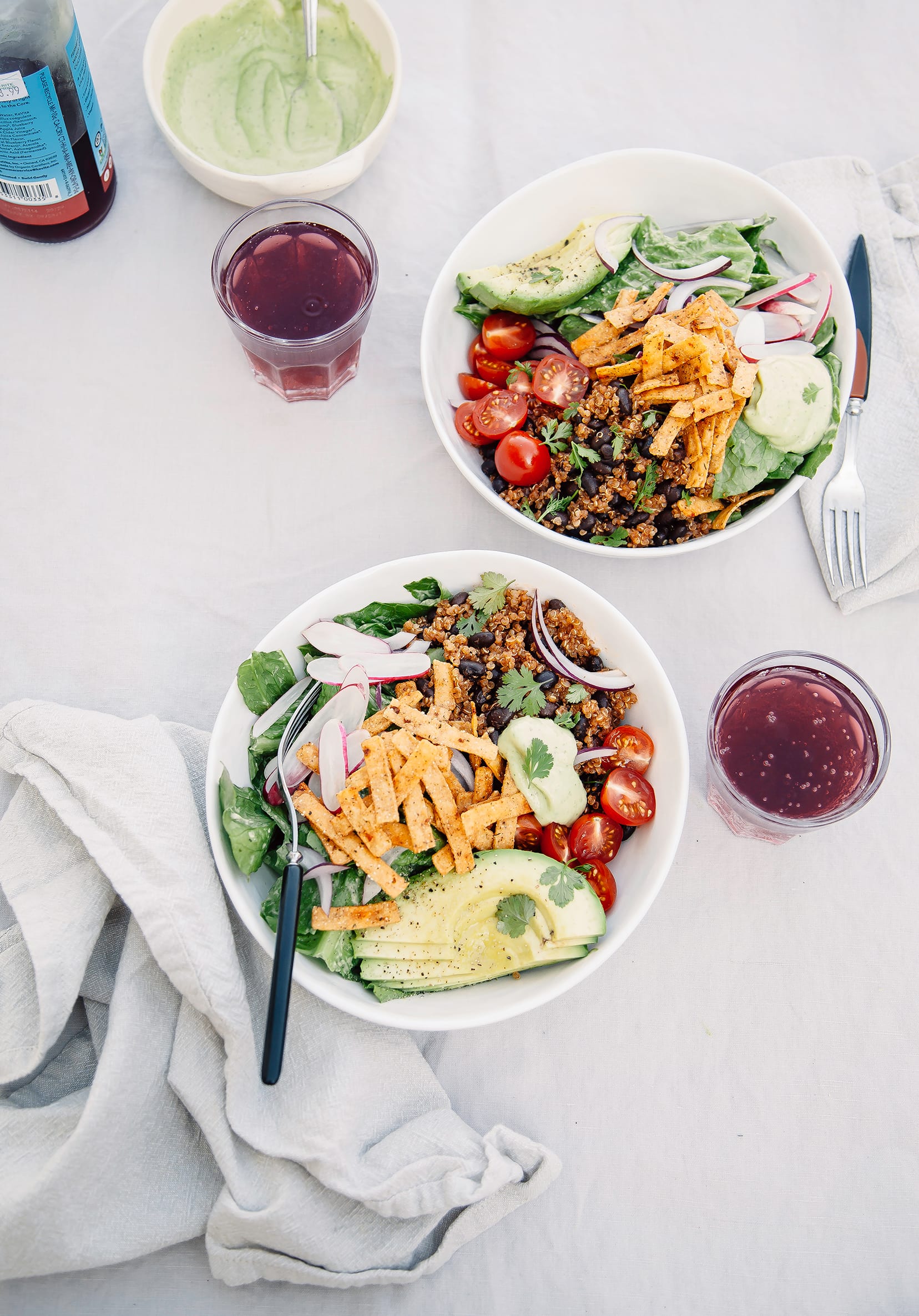 Fresh Taco Salads from "Love Real Food" (vegan recipe) An overhead shot of two taco salads in white bowls. A red drink is served in clear glasses on the side