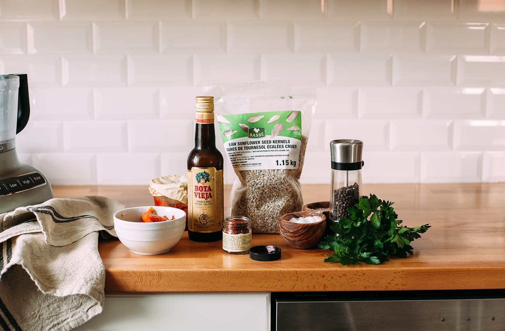 Image shows sunflower romesco sauce ingredients on a wood countertop.